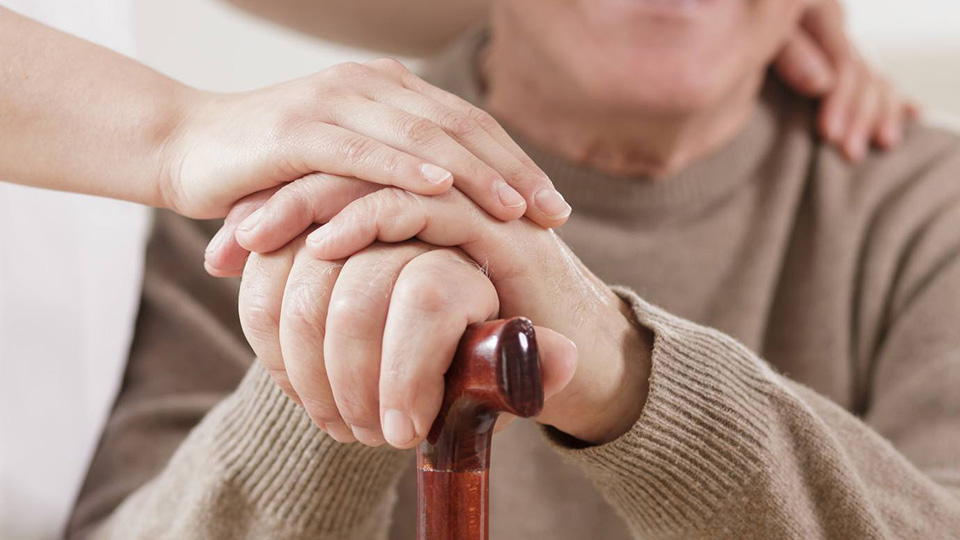 Einfühlsame Pflegerin unterstützt eine ältere Patientin bei täglichen Aktivitäten zu Hause